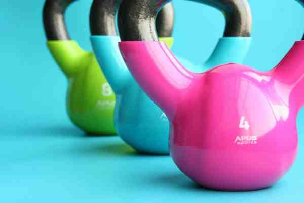 green blue and pink kettle bells on blue surface